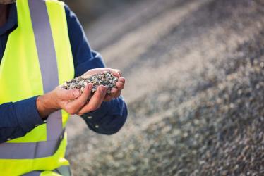Photo of a person in a hi-vis vest looking at aggregates in their hand